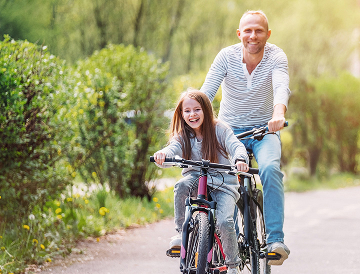Image of father and daughter riding bicycles on a cycle path.